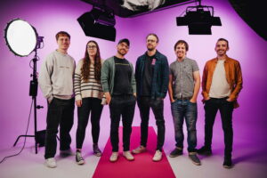 Employees at Briight standing on a photography set in front of a purple background